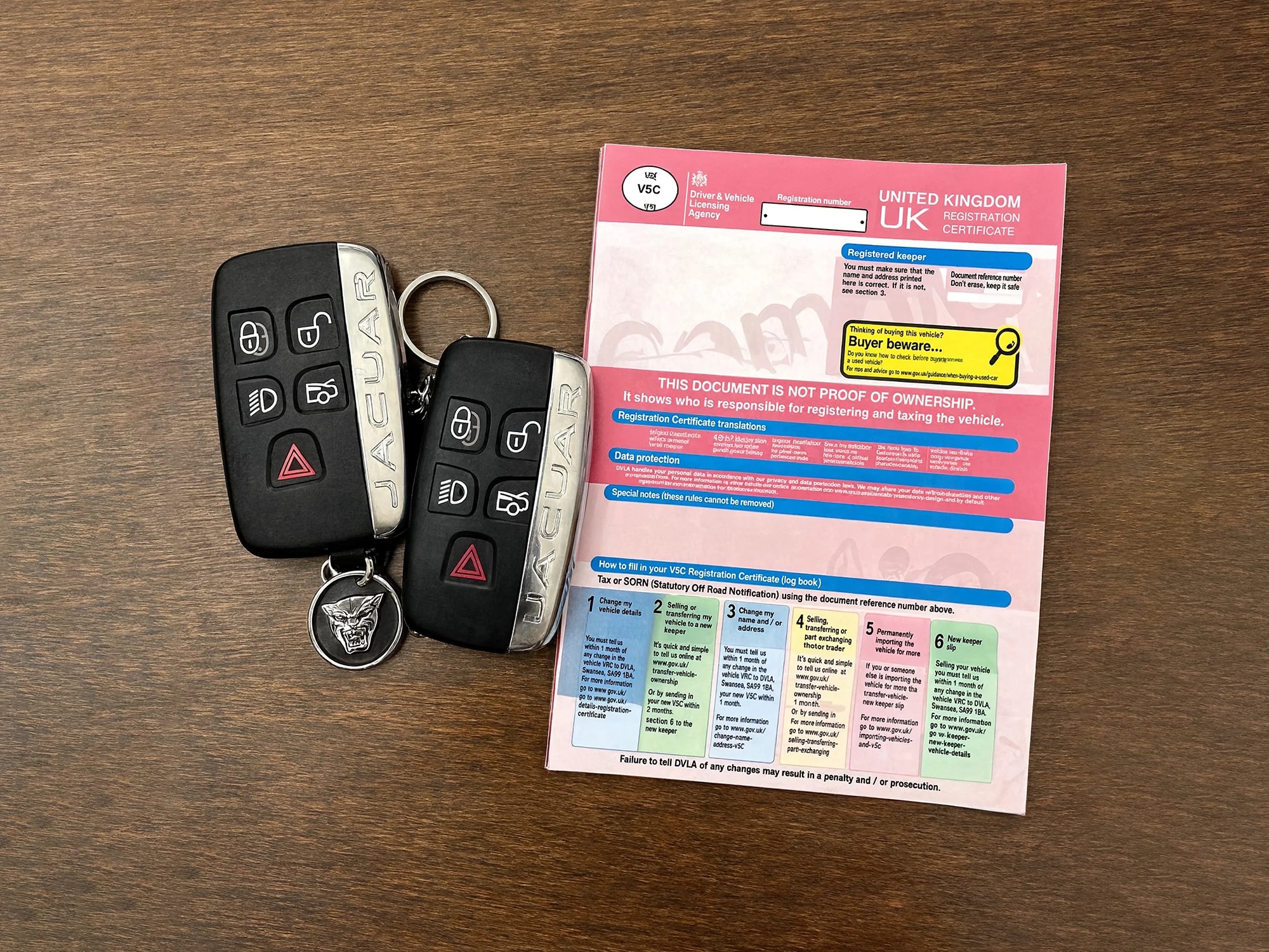 Jaguar keys, V5 logbook and service history on a wooden surface